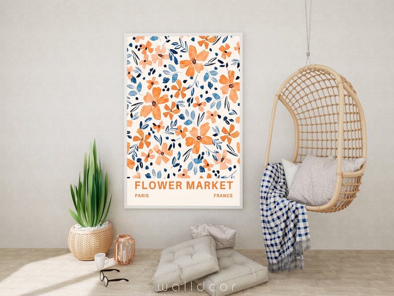 May include: A framed print with a floral pattern in shades of orange and blue. The print has the text "FLOWER MARKET" with "PARIS" and "FRANCE" below it.