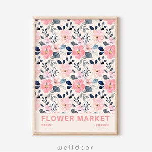 May include: A printable wall art design featuring a floral pattern with pink and blue flowers on a cream background. The text "FLOWER MARKET" is printed in pink at the bottom of the design, with "PARIS" and "FRANCE" printed in black below the text.