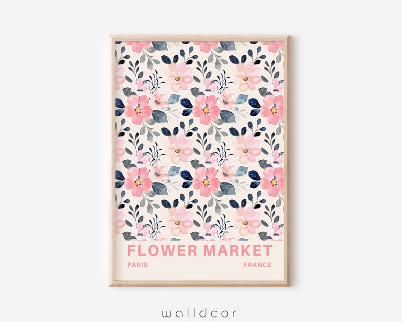 May include: A printable wall art design featuring a floral pattern with pink and blue flowers on a cream background. The text "FLOWER MARKET" is printed in pink at the bottom of the design, with "PARIS" and "FRANCE" printed in black below the text.