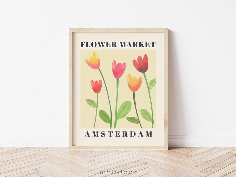 May include: A framed art print featuring a watercolor illustration of tulips in shades of red, pink, and yellow. The text "FLOWER MARKET AMSTERDAM" is displayed in a navy blue font against a cream background.