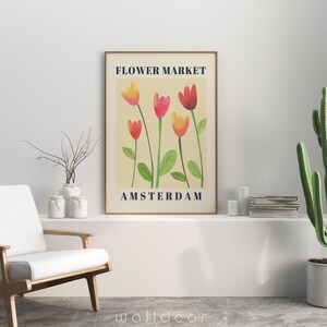 May include: A framed art print featuring a watercolor illustration of tulips in shades of red, pink, and yellow, with green stems and leaves. The text "FLOWER MARKET AMSTERDAM" is displayed in navy blue.