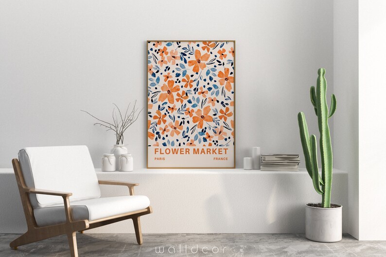 May include: A framed print with a floral pattern in shades of orange and blue. The print has the text "FLOWER MARKET" with "PARIS" and "FRANCE" underneath.