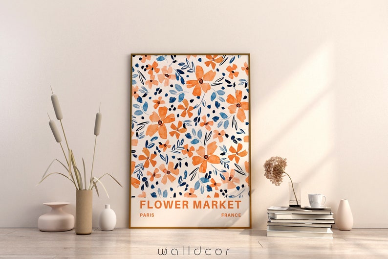 May include: A framed print with a floral pattern in shades of orange, blue, and white. The print has the text "FLOWER MARKET" with "PARIS" and "FRANCE" below it.