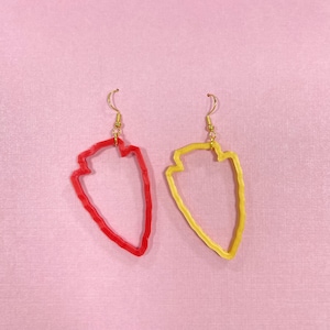 May include: A pair of earrings with a geometric arrowhead design. One earring is red and the other is yellow.
