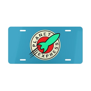 May include: A light blue license plate featuring the Planet Express logo. The logo is a circular design with a red center, a green rocket, and the words "Planet Express" in a circular font. The plate has four mounting holes.