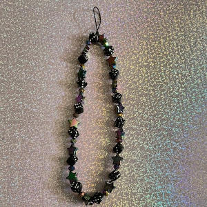 May include: A black and iridescent phone charm with dice and star beads.
