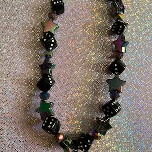 May include: A black and iridescent necklace with black dice and star-shaped beads.