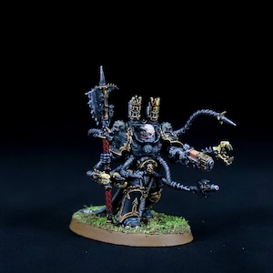 Könnte beinhalten: Eine schwarz und gold lackierte Miniatur eines Chaos Space Marines mit mehreren mechanischen Armen und einer großen Axt.