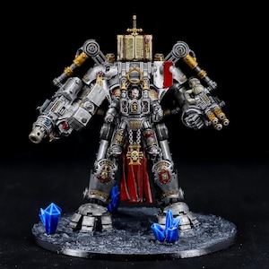 Puede incluir: Figura de robot en miniatura detallada, principalmente plateada con detalles dorados y rojos, sobre una base texturizada con formaciones de cristal azul. El robot tiene grandes armas montadas en los brazos y una estructura similar a un libro en la cabeza.