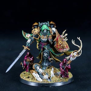 Puede incluir: Figura en miniatura detallada de un guerrero con armadura verde y negra, sosteniendo una espada y un escudo. La figura está rodeada de figuras más pequeñas y elementos decorativos, todo sobre una base circular. La figura tiene un casco verde y detalles dorados.
