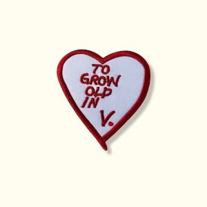 May include: Red heart-shaped patch with white fabric and red embroidered text that reads "To Grow Old In V."