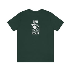 May include: Dark green t-shirt with a white graphic. The graphic includes a ninja character, a rising graph, and the text "QBO NINJA". The ninja is shown in motion, with dollar signs and speed lines.