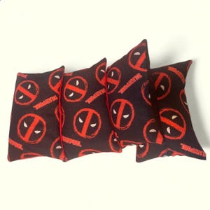 May include: Four black bean bags with red trim and a repeating pattern of the Deadpool logo and the word "Deadpool" in red.