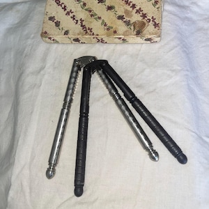 May include: An assortment of nutcrackers with silver and black handles, and a decorative box with a floral pattern. The nutcrackers are made of metal and have a classic design, perfect for cracking nuts.