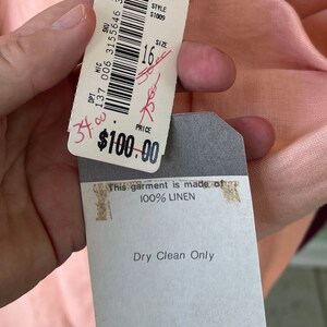 May include: A pink linen top with a white tag that says "Dillard's" and "This garment is made of 100% LINEN". The tag also says "Dry Clean Only" and has the size "16" and style number "S1009" printed on it.