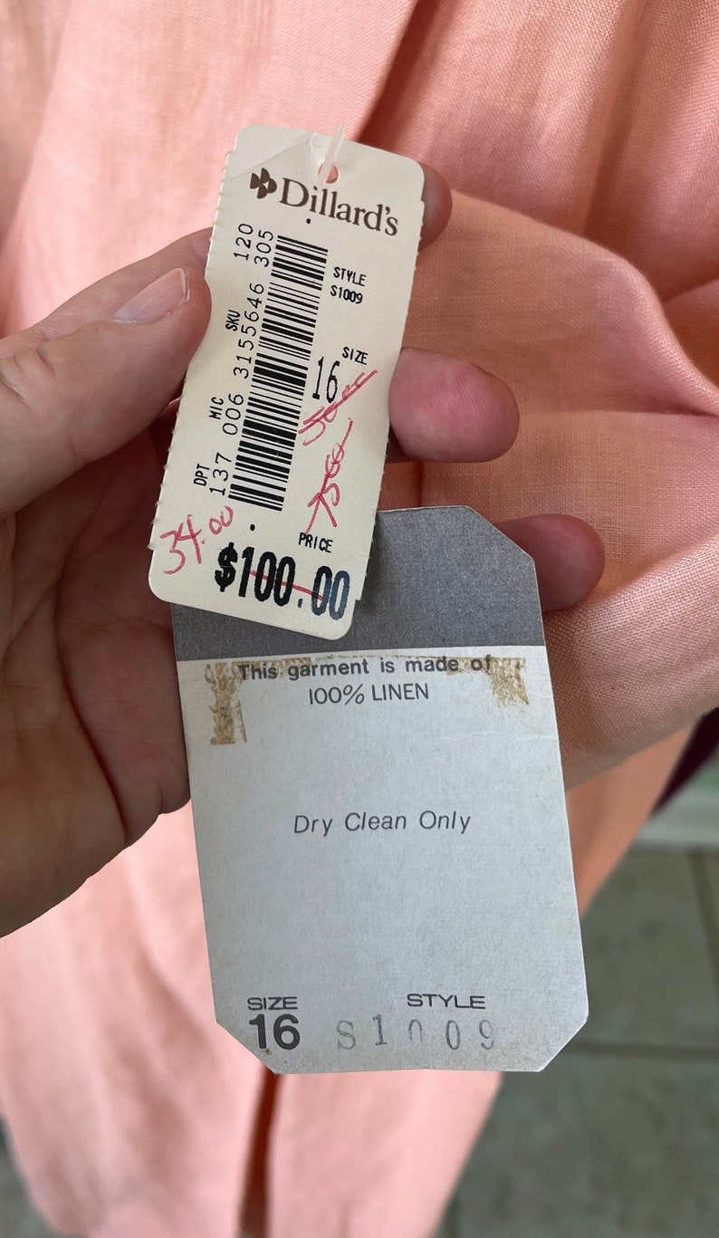 May include: A pink linen top with a white tag that says "Dillard's" and "This garment is made of 100% LINEN". The tag also says "Dry Clean Only" and has the size "16" and style number "S1009" printed on it.