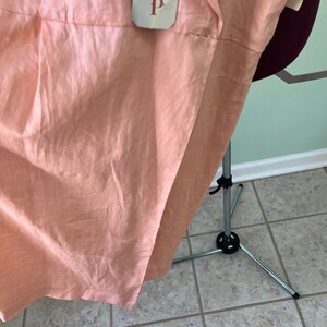 May include: A peach-colored linen dress with a white tag that says "A.P." on it.