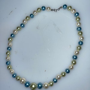 May include: A multi-colored pearl necklace with blue, white, and green pearls.