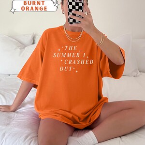 Pode incluir: Camiseta laranja queimado com o texto branco "THE SUMMER I CRASHED OUT". A camiseta &eacute; de cor confort&aacute;vel e tem um ajuste descontra&iacute;do. A imagem tamb&eacute;m mostra o nome da cor "BURNT ORANGE".