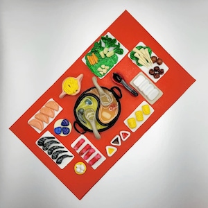 May include: A red tray with various food items made of play dough, including a hot pot, vegetables, dumplings, and noodles. The tray is perfect for pretend play and imaginative cooking.