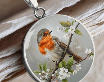 May include: A stainless steel necklace with a round pendant featuring a robin perched on a branch with white blossoms. The robin has a red breast and gray wings.