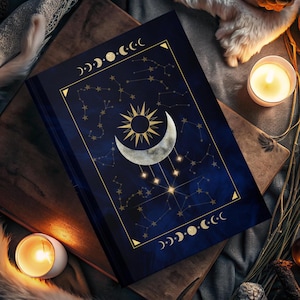 以下が含まれることがあります： 金色の三日月と太陽のデザインが施された濃い青色のジャーナル。表紙には星座のパターンと金色の三日月の縁取りが施されています。