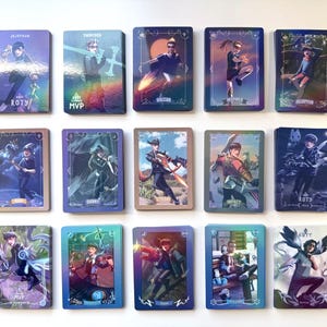 A set of 15 holographic trading cards featuring colorful illustrations of various North American League of Legends esports LCS professional players. The cards depict the players in dynamic poses as their favorite or iconic champions from different years. The cards have borders based on the player's team colors.