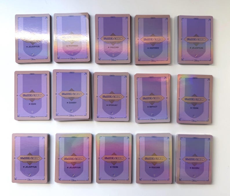 May include: A set of 15 holographic trading cards featuring various characters from the Disney movie "Descendants". Each card has a purple background with a gold border and features a character from the movie. The cards are arranged in three rows of five.