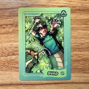 A trading card featuring lolesports LCS and LCK professional player Song Suhyeong, aka Quad, in the FlyQuest 2025 green jersey. He is drawn laying on grass with a smile, extending an arm upward as his signature League of Legends champion, Mythic Cassiopeia, so he has a snake tail. The card has a green gradient border with the text "QUAD" and the Mid Lane icon at the bottom right, 'MYTHIC CASSIOPEIA' bottom left, the LTA North logo and 2025 top right, and the FLYQUEST name and logo at top left.