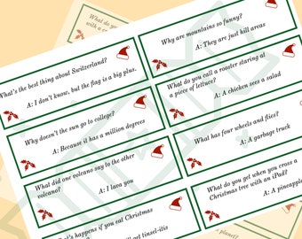 May include: A collection of Christmas-themed joke cards. Each card features a green border, a Santa hat, and a sprig of holly. The jokes and answers are printed in black text on a white background. The cards are arranged on a light yellow surface.