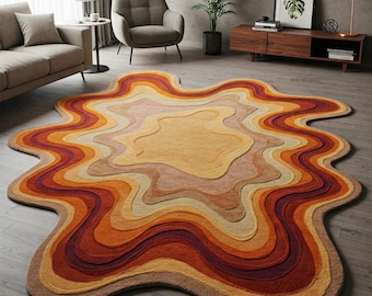 May include: A large, abstract area rug with a wavy, organic shape. The rug features a multi-colored design with shades of orange, red, brown, and beige. The rug has a textured, hand-woven look.