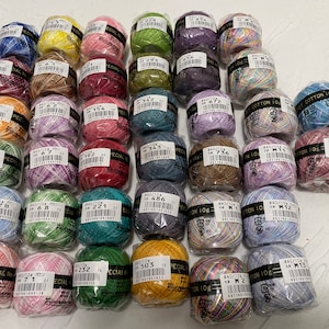 May include: A collection of 36 colorful spools of thread, each with a black label and white text. The labels include numbers and the words "Special Cotton 10g".