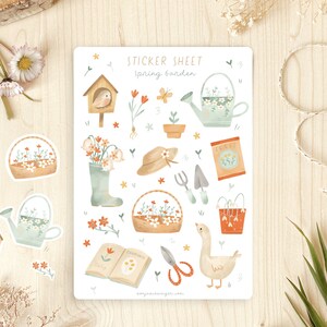 May include: A sticker sheet with a spring garden theme. The sheet features illustrations of a birdhouse, watering can, flowers, gardening tools, a goose, and the text "Spring Garden". The stickers are in soft pastel colours.