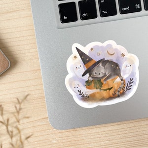 May include: A Halloween-themed sticker featuring a gray cat wearing a witch hat, resting on a carved pumpkin. The sticker includes ghosts, stars, and a crescent moon, all set against a light blue background. The design has a watercolor style.