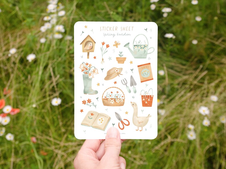 May include: A sticker sheet with a spring garden theme. The sheet features illustrations of gardening tools, flowers, a birdhouse, a watering can, and a goose. The text "STICKER SHEET spring garden" is at the top.