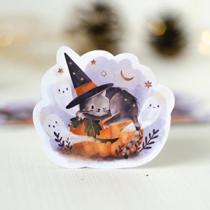May include: A whimsical Halloween sticker featuring a gray cat wearing a witch hat, resting on an orange pumpkin. The design includes friendly ghosts, stars, and a crescent moon, creating a spooky yet cute aesthetic.