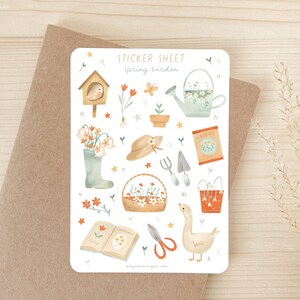 May include: A sticker sheet with a spring garden theme. The sheet features illustrations of gardening tools, flowers, a birdhouse, a watering can, a goose, and the text "Spring Garden". The color palette includes soft greens, oranges, and browns.