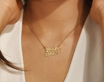 May include: Gold necklace with two names, "Brielle" and "Lennon", written in cursive script with a small heart charm between the names.