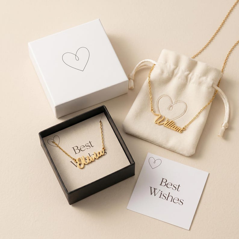 Peut inclure: Colliers dor&eacute;s avec des noms, pr&eacute;sent&eacute;s dans une bo&icirc;te noire, une bo&icirc;te cadeau blanche et une pochette &agrave; cordon. Les colliers sont personnalis&eacute;s avec les noms "William" et "Olivia". Une carte "Best Wishes" est &eacute;galement pr&eacute;sente.
