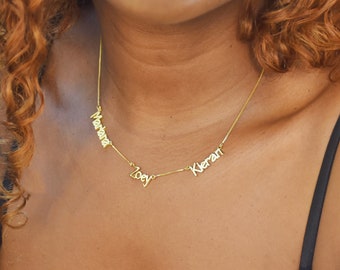 May include: A gold chain necklace with three names, "Mariana", "Zoey", and "Kieran", spelled out in cursive.