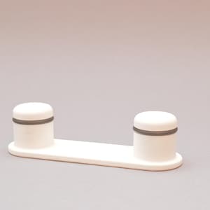 Può includere: Mensola in plastica bianca con due montanti rotondi bianchi, ciascuno con una fascia grigia attorno alla parte superiore.