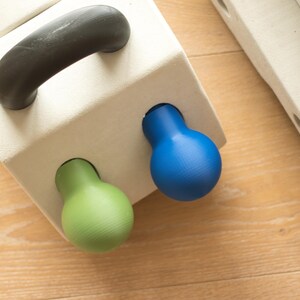 Può includere: Un blocco bianco con una maniglia nera e tre pomelli colorati. I pomelli sono verdi, blu e gialli.