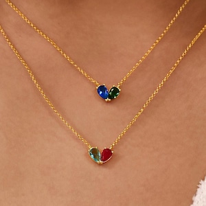 May include: Two gold-tone chain necklaces, each featuring a small pendant shaped like a heart. The top necklace has a blue and green heart pendant, while the bottom necklace features a light blue and red heart pendant, both with delicate links.