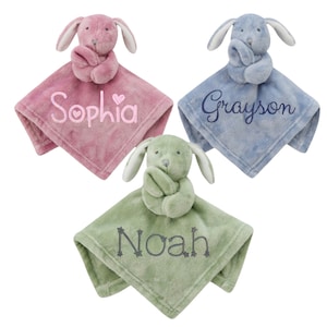Puede incluir: Tres mantas de seguridad de peluche en forma de conejo en rosa, azul y verde con los nombres bordados "Sophia", "Grayson" y "Noah".