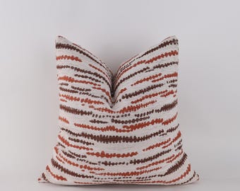 May include: A decorative throw pillow with a white background and a pattern of rust and brown dashes. The pillow has a soft, textured appearance and is designed to add a touch of style to any living space.