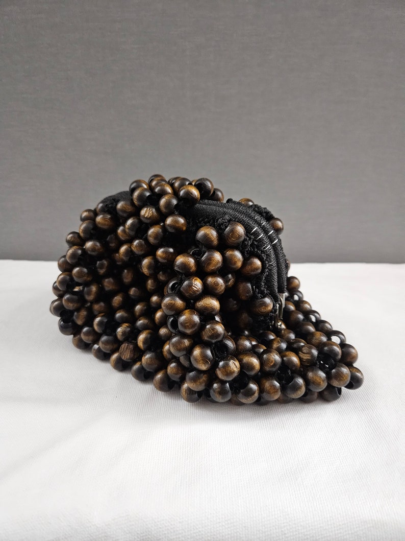 May include: A brown wooden beaded purse with a black zipper closure.