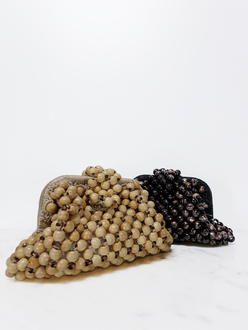 May include: Two beaded purses, one in natural wood tones and one in black. Both purses are made of small, round beads woven together.