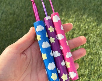 Ganchillos de crochet personalizados con forma de nubes y estrellas azules, moradas y rosas, hechos a mano con arcilla polimérica brillante.