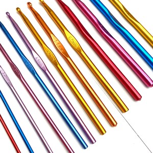 Op de afbeelding: Een verzameling kleurrijke haaknaalden in verschillende maten. De haken zijn gemaakt van metaal en hebben een gladde, glanzende afwerking. De kleuren zijn rood, blauw, goud, paars en roze. De maten staan in millimeters aangegeven.