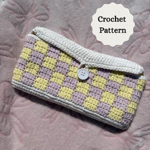 May include: A crocheted case with a checkerboard pattern in pastel yellow and lavender. The case has a white border and flap, secured by a white button. The text "Crochet Pattern" is in a white circle.